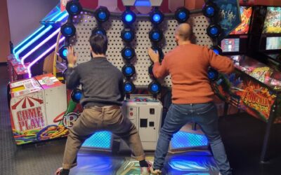 deux personne de dos qui jouent à un jeu d'arcade